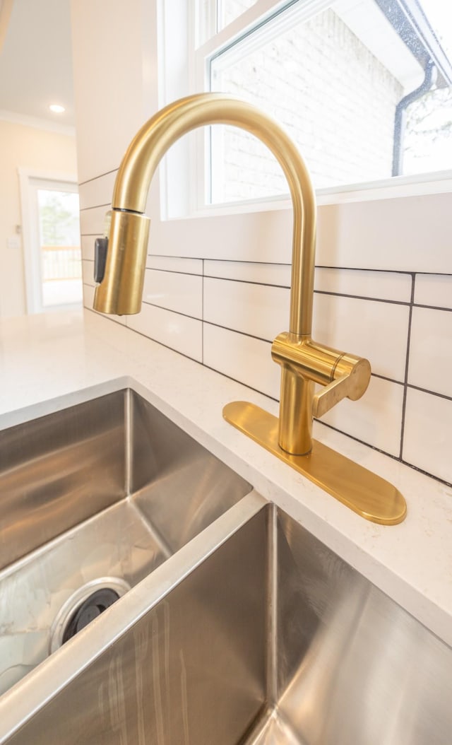 room details with light countertops, a sink, white cabinets, and decorative backsplash