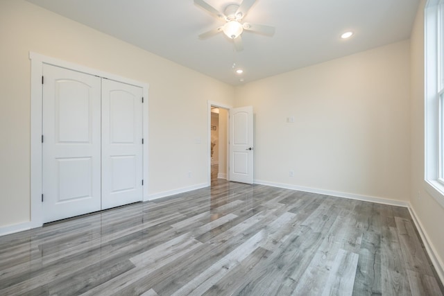 unfurnished bedroom with recessed lighting, a closet, light wood-style flooring, and baseboards