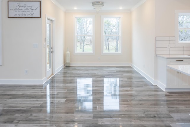 unfurnished dining area with a healthy amount of sunlight, baseboards, and crown molding