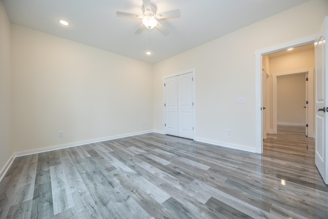 unfurnished bedroom with baseboards, a closet, recessed lighting, and light wood-style floors