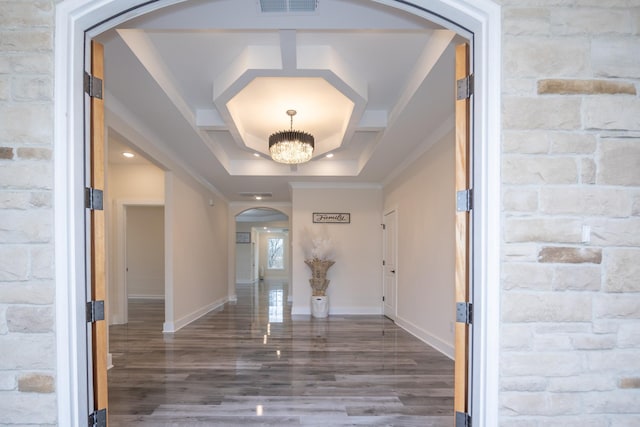 foyer featuring arched walkways, dark wood finished floors, a chandelier, coffered ceiling, and baseboards