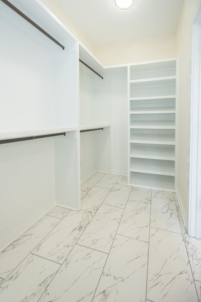 walk in closet featuring marble finish floor