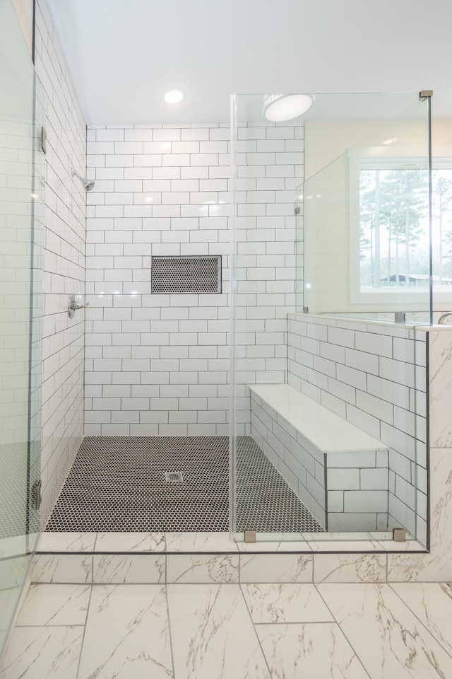 bathroom featuring marble finish floor and a shower stall