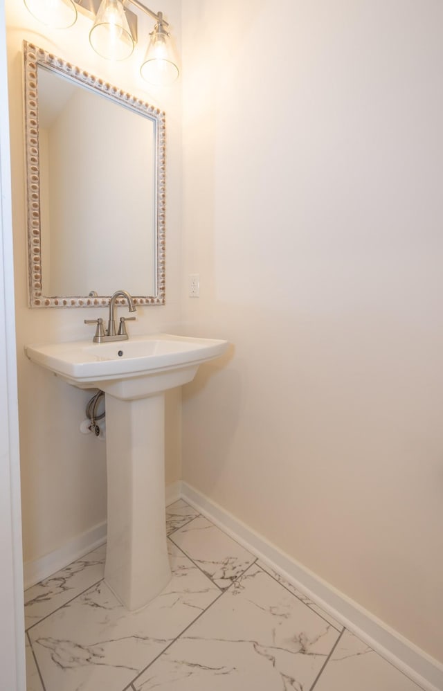 bathroom with marble finish floor, a sink, and baseboards