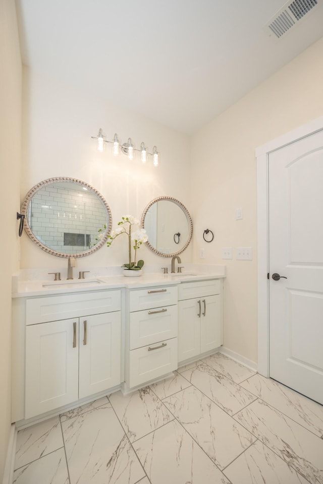 bathroom featuring marble finish floor, visible vents, a sink, and double vanity