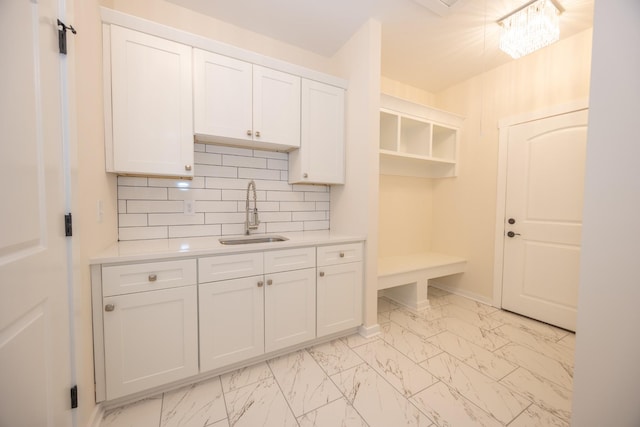 kitchen with marble finish floor, light countertops, a sink, and white cabinets