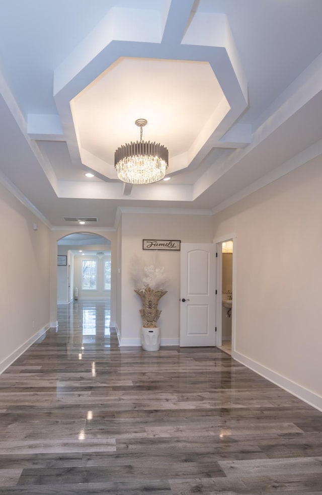 hall featuring arched walkways, baseboards, and a notable chandelier