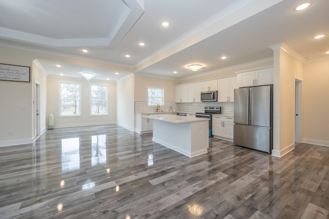 kitchen featuring open floor plan, stainless steel appliances, light countertops, white cabinetry, and backsplash