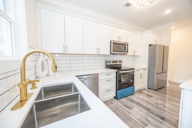 kitchen featuring a sink, stainless steel appliances, light countertops, and white cabinetry