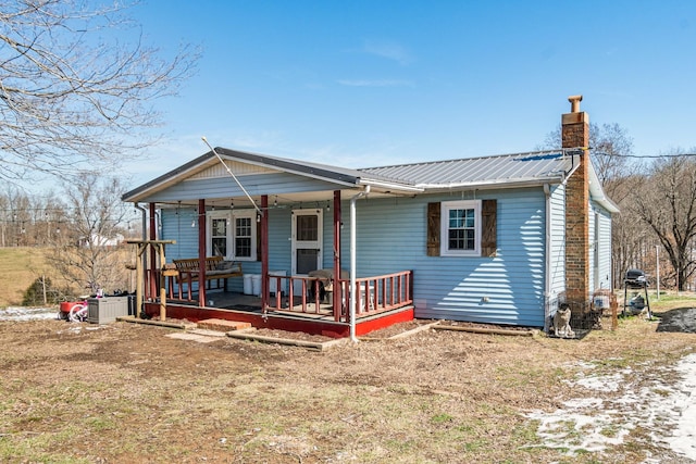 view of front of property with covered porch, a chimney, and metal roof