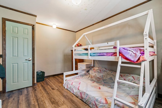 bedroom featuring baseboards, wood finished floors, and crown molding