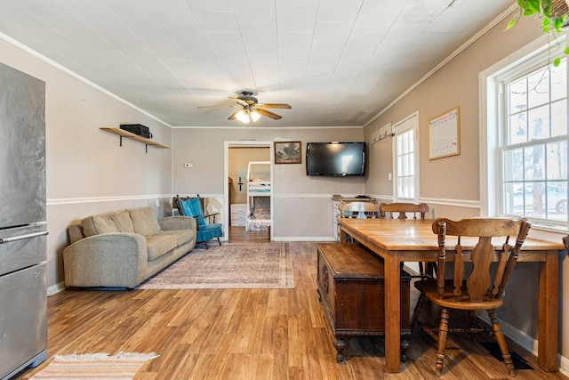 living area featuring light wood-style floors, a ceiling fan, and crown molding