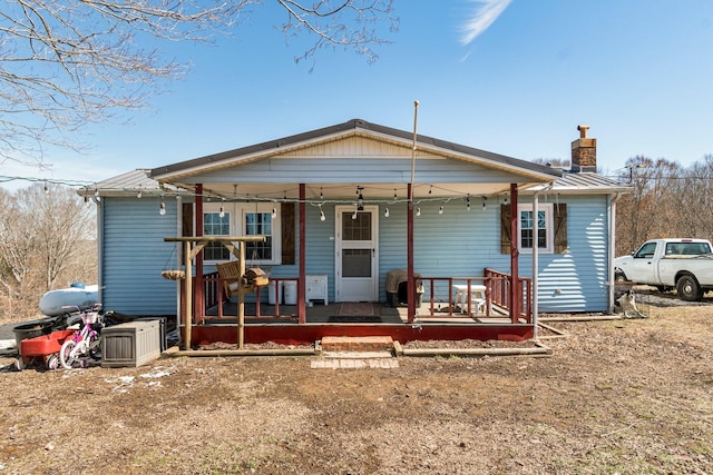 view of front facade featuring a porch, metal roof, and a chimney