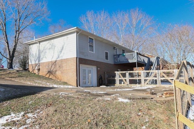 back of house featuring brick siding, a deck, and french doors