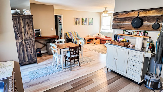 kitchen with ceiling fan, light wood-type flooring, dark countertops, and white cabinetry