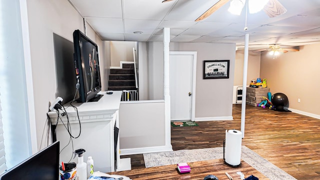 office featuring ceiling fan, wood finished floors, a paneled ceiling, and baseboards