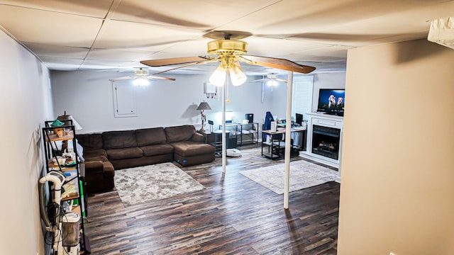 living room featuring dark wood-style floors, a fireplace, a paneled ceiling, and a ceiling fan