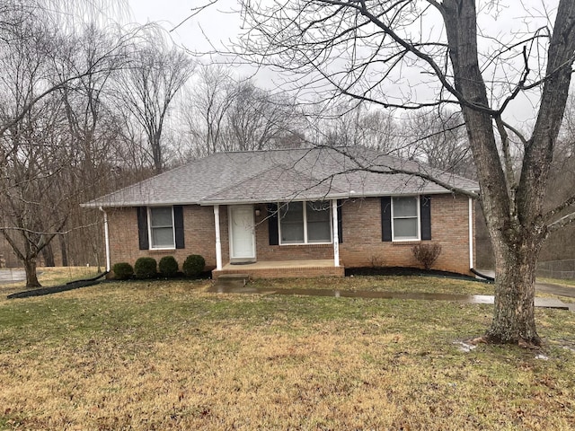 ranch-style house with brick siding, a front lawn, and roof with shingles