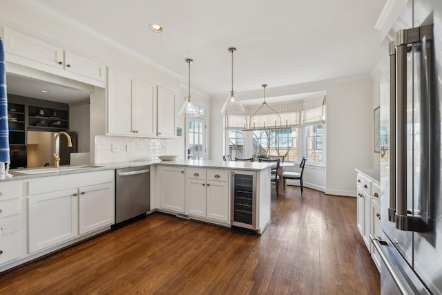 kitchen featuring wine cooler, a peninsula, a sink, freestanding refrigerator, and dishwasher