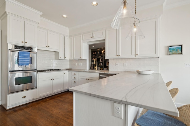 kitchen with a peninsula, double oven, and white cabinetry