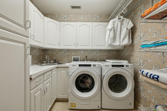 washroom with a sink, visible vents, cabinet space, washing machine and clothes dryer, and wallpapered walls