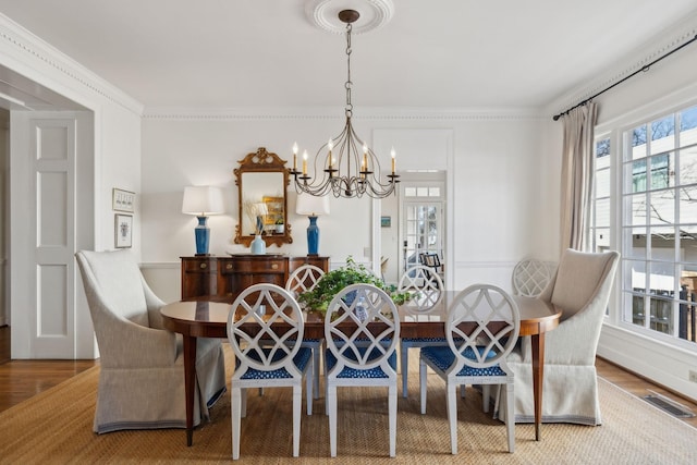 dining space with ornamental molding, wood finished floors, and a notable chandelier