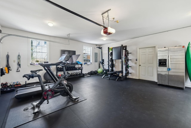 workout area featuring a garage, electric panel, and baseboards