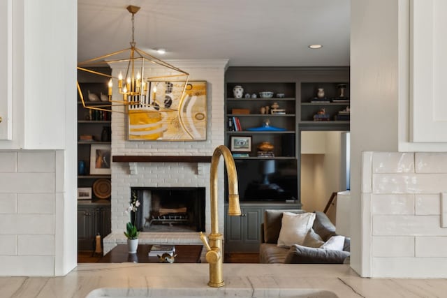 living room with built in shelves, a fireplace, and a notable chandelier