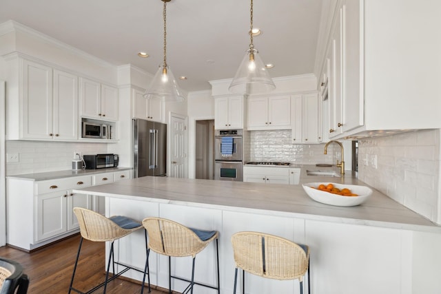 kitchen featuring a peninsula, white cabinets, stainless steel appliances, and a sink