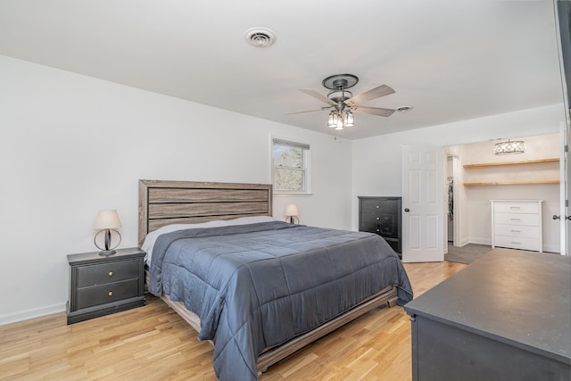 bedroom featuring ceiling fan, wood finished floors, visible vents, and baseboards