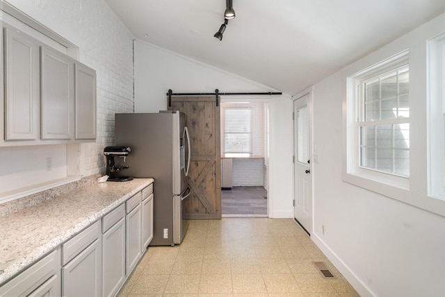 kitchen featuring baseboards, visible vents, stainless steel fridge with ice dispenser, vaulted ceiling, and light floors