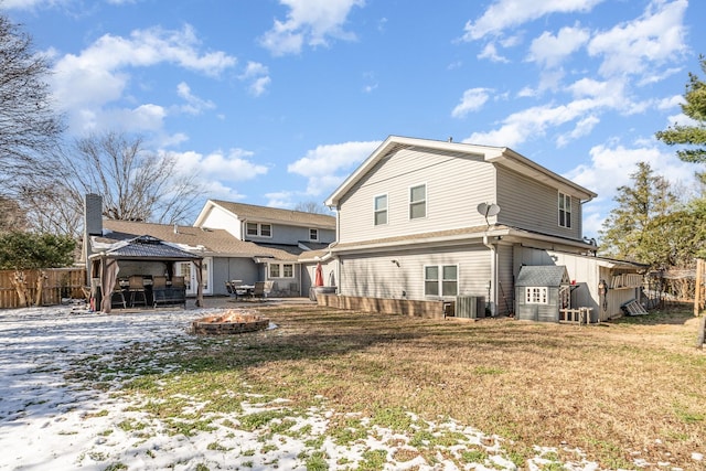 rear view of house with a yard, a gazebo, an outdoor fire pit, fence, and cooling unit