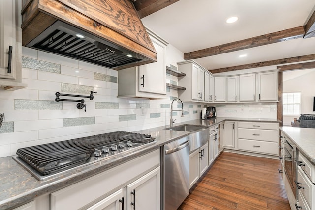 kitchen featuring white cabinets, custom range hood, stainless steel appliances, and a sink