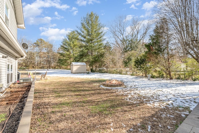 view of yard featuring a fire pit, a storage unit, an outdoor structure, and fence