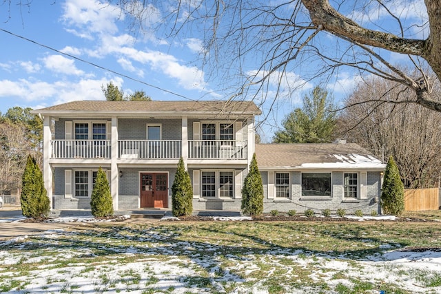 view of property featuring entry steps, brick siding, a yard, and a balcony