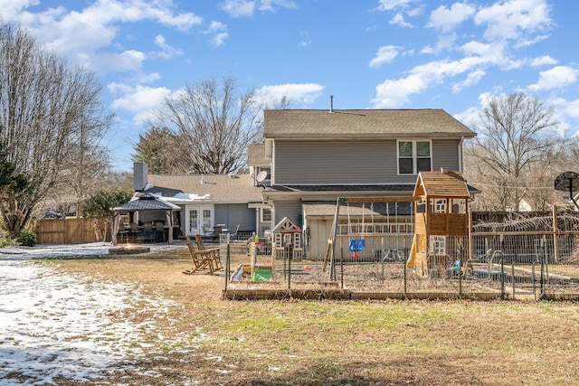 back of property with a playground, fence, a gazebo, and a lawn