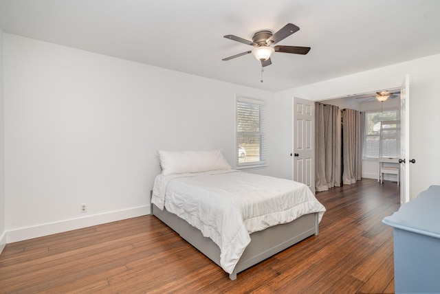 bedroom featuring dark wood-style floors, multiple windows, a ceiling fan, and baseboards