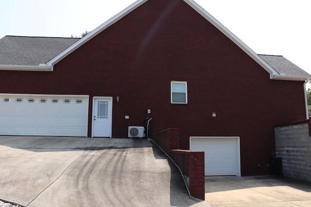 view of side of property with a garage, ac unit, concrete driveway, and roof with shingles