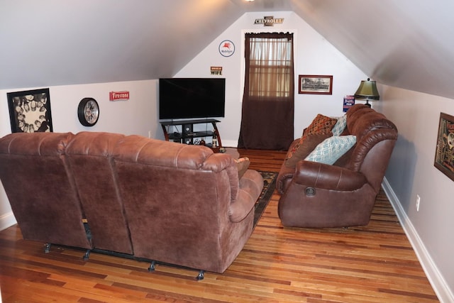 living area featuring vaulted ceiling, wood finished floors, and baseboards