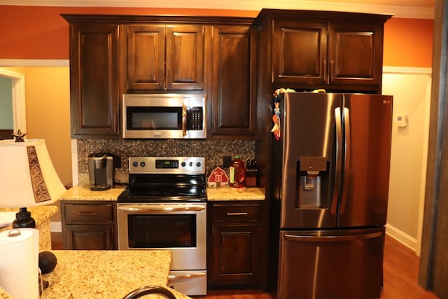 kitchen featuring baseboards, appliances with stainless steel finishes, decorative backsplash, light stone countertops, and dark wood-style floors