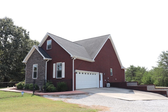 view of property exterior with driveway, fence, a lawn, and brick siding