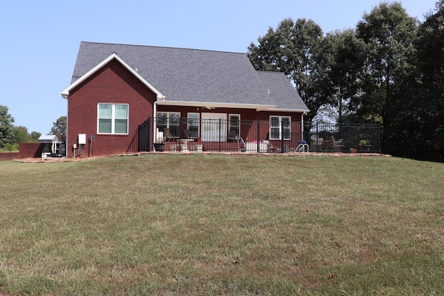 view of front facade featuring brick siding, fence, and a front yard