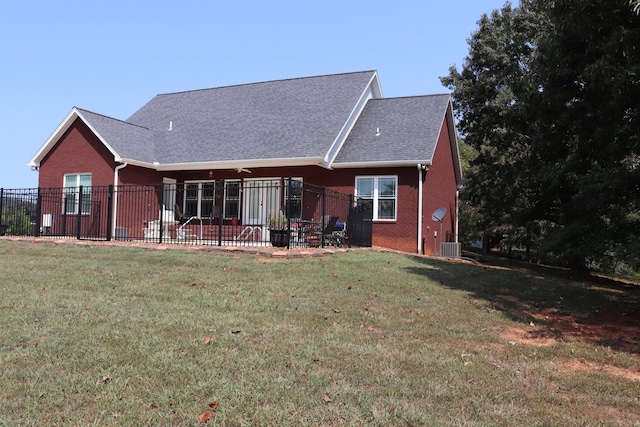 view of front of house featuring brick siding, a front lawn, a shingled roof, and fence