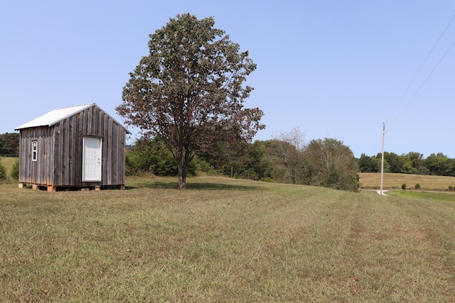 view of yard featuring a shed, a rural view, and an outbuilding