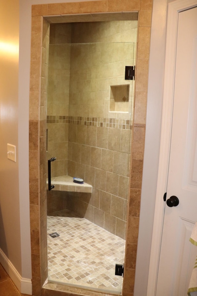 full bathroom featuring a shower stall and baseboards