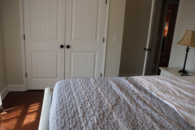 bedroom with dark wood-style floors, a closet, and baseboards