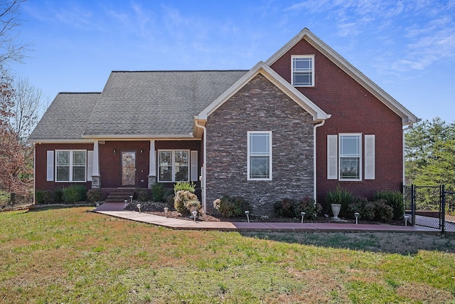 view of front of home with brick siding, fence, a front lawn, and roof with shingles