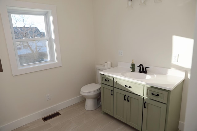 bathroom featuring visible vents, toilet, vanity, and baseboards