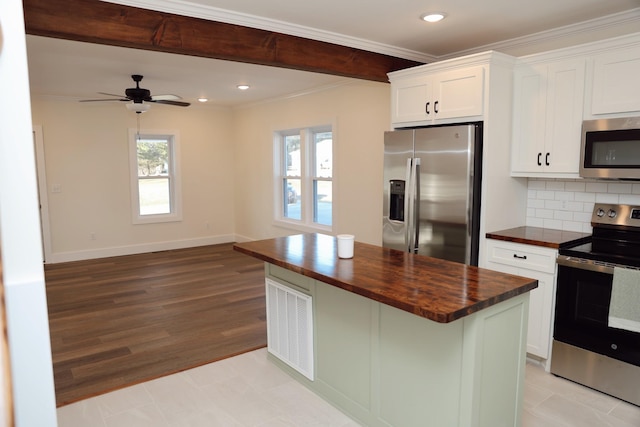 kitchen with tasteful backsplash, white cabinets, a kitchen island, appliances with stainless steel finishes, and butcher block countertops