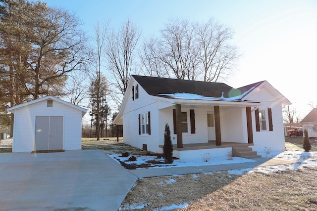 view of front of home with covered porch, a shed, stucco siding, and an outdoor structure